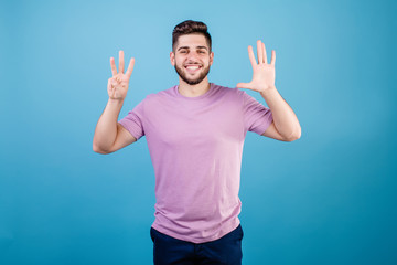 Fototapeta premium smiling man showing eight fingers isolated on blue background