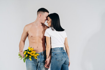Close up portrait young couple with yellow flowers isolated on white background. lovely couple embracing with dreamy amorous expression. Celebrating valentine , woman's day.