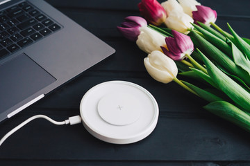 Workspace with laptop, wireless charging for your smartphone and Tulip flowers.
