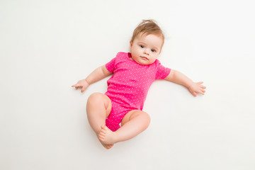 healthy baby girl in a pink bodysuit sits on a white background. space for text
