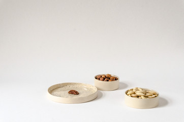 Three white ceramic bowls full of nuts, hazelnuts, almonds