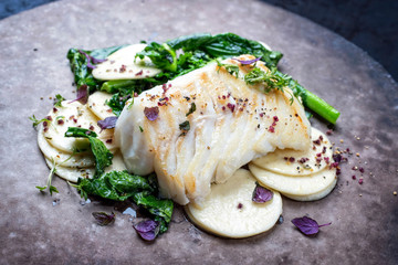 Gourmet fried European skrei cod fish filet with rapini broccoli rabe and creoxetti pasta as...