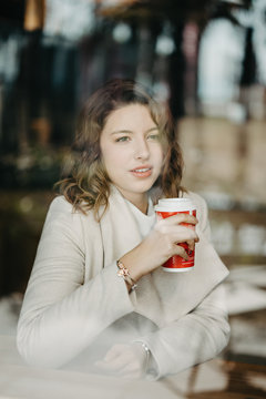 Beautiful young girl sitting and enjoing coffee in restaurant