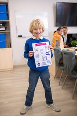 Blond boy standing and holding paper with physics drawings