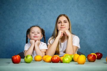 Fototapeta na wymiar Little girl and mom play with fruits and fool around. They are wearing t-shirts