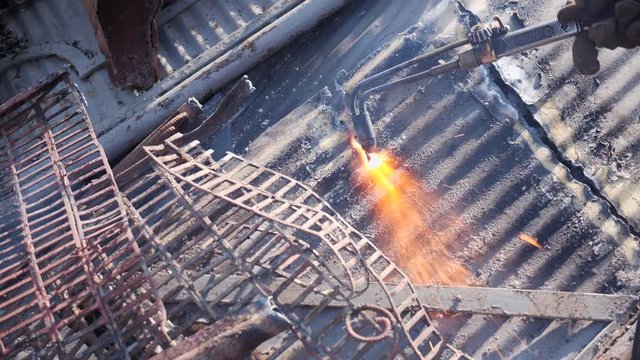 Cutting metal sheet at the scrap yard with oxygen cutter, close up - waste management and recycling metals