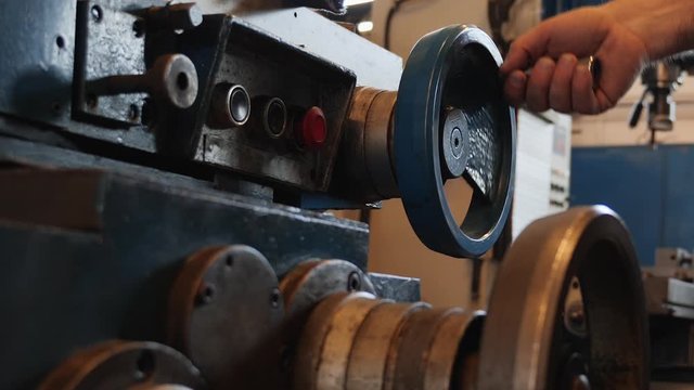 Male hand adjusting industrial machine rotating a wheel - close up, camera zoom out