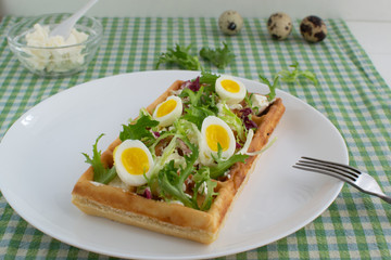 Belgian waffles with boiled quail eggs, mix of green leaves and cheese.