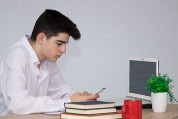 teenage student with mobile phone at desk