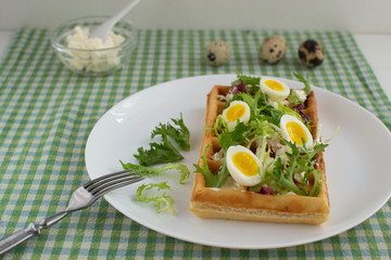 Belgian waffles with boiled quail eggs, mix of green leaves and cheese.