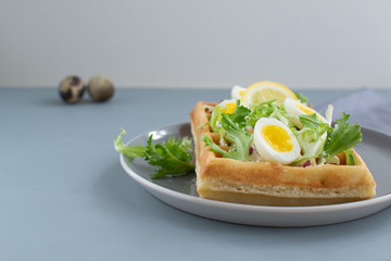 Belgian waffles with boiled quail eggs, mix of green leaves and cheese.