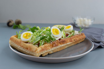 Belgian waffles with boiled quail eggs, mix of green leaves and cheese.
