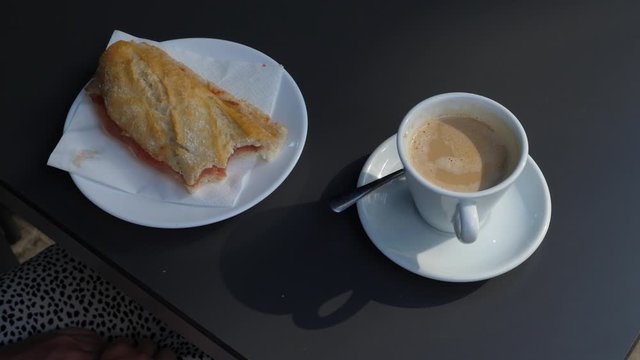 Typical meal at street cafe, Bocadillo con jamon iberico and cup of coffee stay at table, handheld shot. Popular breakfast or refreshment meal at Spain