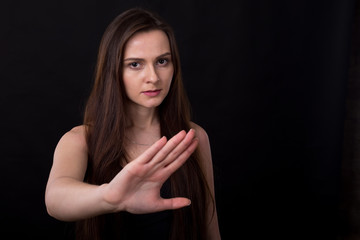 Obraz premium No, this is a failure! Young woman makes a hand gesture forward sign of failure and denial. She is experiencing negative emotions, standing on a black background.