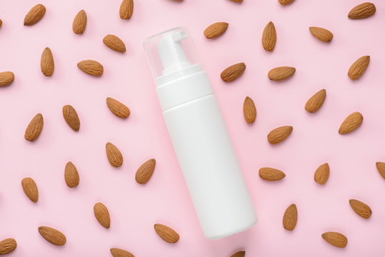 Gel with almond extract concept. Top above overhead view photo of bottle with place for label and lot many nuts around isolated over tender fresh pastel background