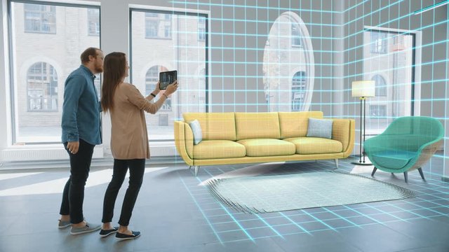 Decorating Apartment: Lovely Young Couple Use Digital Tablet with Augmented Reality Interior Design Software to Choose 3D Furniture for their Home. People Pick Sofa, Table and Lighting for Living Room