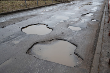 Ugly asphalt road with big holes and  pools