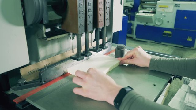 Typography worker is using a machine to punch holes in paper