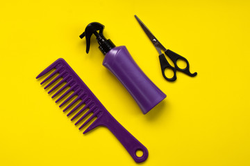 Beauty topic:  stylist scissors, hairspray and stylist's comb over yellow background.  Fashion and style concept.