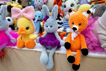 Knitted colored handmade toys duck, rabbit and fox on display in the gifts and crafts market. To illustrate hobbies, creativity, leisure