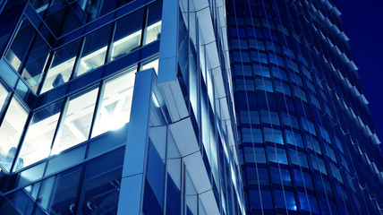 Night architecture - building with glass facade.Blue color of night lights. Modern building in  business district. Concept of economics, financial. Photo of commercial office building exterior. Abstra