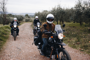 Fototapeta na wymiar Man on touring motorcycle in field or forest. Friends during motorcycle trip or adventure exploring. Bikers on weekend trip, have fun on dirt bikes