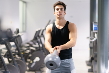 Fototapeta na wymiar Man training in a gym using a kettlebell