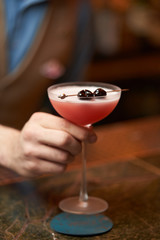 Expert barman is making cocktail at night club, close-up.