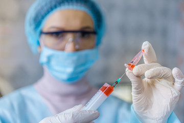 A doctor is preparing an injection of a vaccine against coronavirus.
