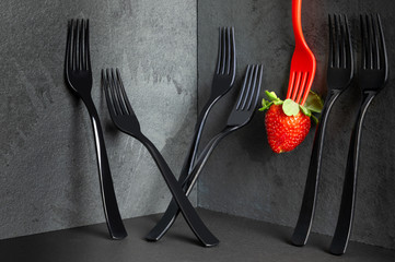 Minimalistic elegant, black forks and a strawberry on black background