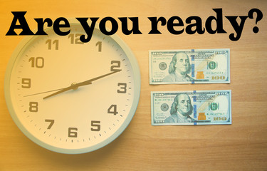 Analog clock and dollars on a wooden background. Banknotes are on the clock and next. Macro. Top and side view. The clock is 20:05, 08:05.  Copy Space