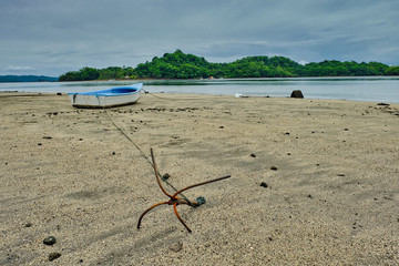 Fototapeta na wymiar Rhebarb anchored colorful fishing boat anchored on an empty beach at low tide