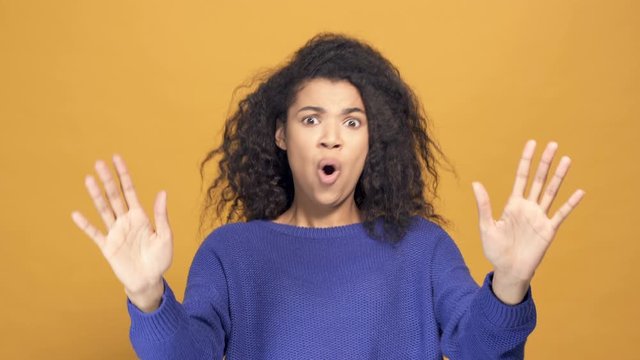 Close up portrait of excited  afro american woman showing wow, wonder emotion. Yellow background.