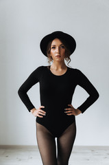 Beautiful ukrainian girl in a black bodysuit and black hat on white background