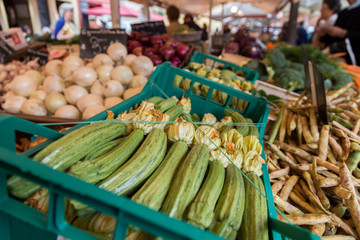 Fresh courgettes and zucchini with flowers displayed in a market stall in Nice, France, showcasing seasonal vegetables and local produce.