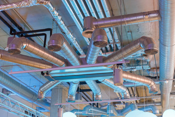 Industrial ventilation system ducts and pipes and electrical communications under ceiling - obrazy, fototapety, plakaty