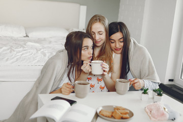 Obraz na płótnie Canvas Girls in a pajamas. Friends have fun at home. Ladies drinking a coffee.
