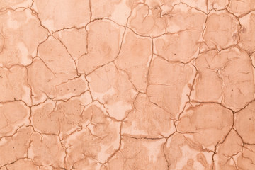 Close up of a textured, terracotta, cracked earth clay wall background