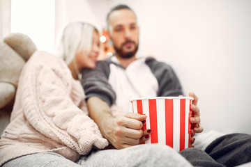 Obraz premium Cute couple in a bedroom. Lady in a pink sweater. Pair at home with a popcorn