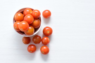 Fresh cherry tomato, displayed in containers on white wooden background