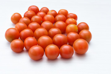 Fresh cherry tomato, displayed in containers on white wooden background
