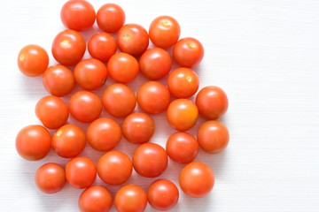 Fresh cherry tomato, displayed in containers on white wooden background