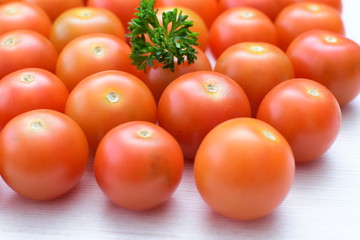 Fresh cherry tomato, displayed in containers on white wooden background