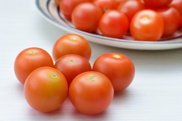 Fresh cherry tomato, displayed in containers on white wooden background