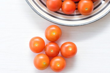 Fresh cherry tomato, displayed in containers on white wooden background