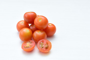 Fresh cherry tomato, displayed in containers on white wooden background