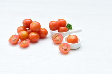 Fototapeta na wymiar Fresh cherry tomato, displayed in containers on white wooden background