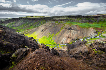 Fototapeta na wymiar Wonderful icelandic nature landscape. View from the top. High mountains, mountain river and green grassland. Green meadows. Iceland.