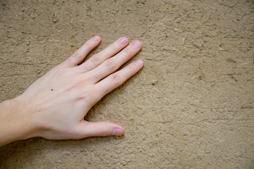Hand of a young women stroking an environmentally friendly wall with clay plaster