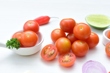 Fresh cherry tomato, displayed in containers on white wooden background